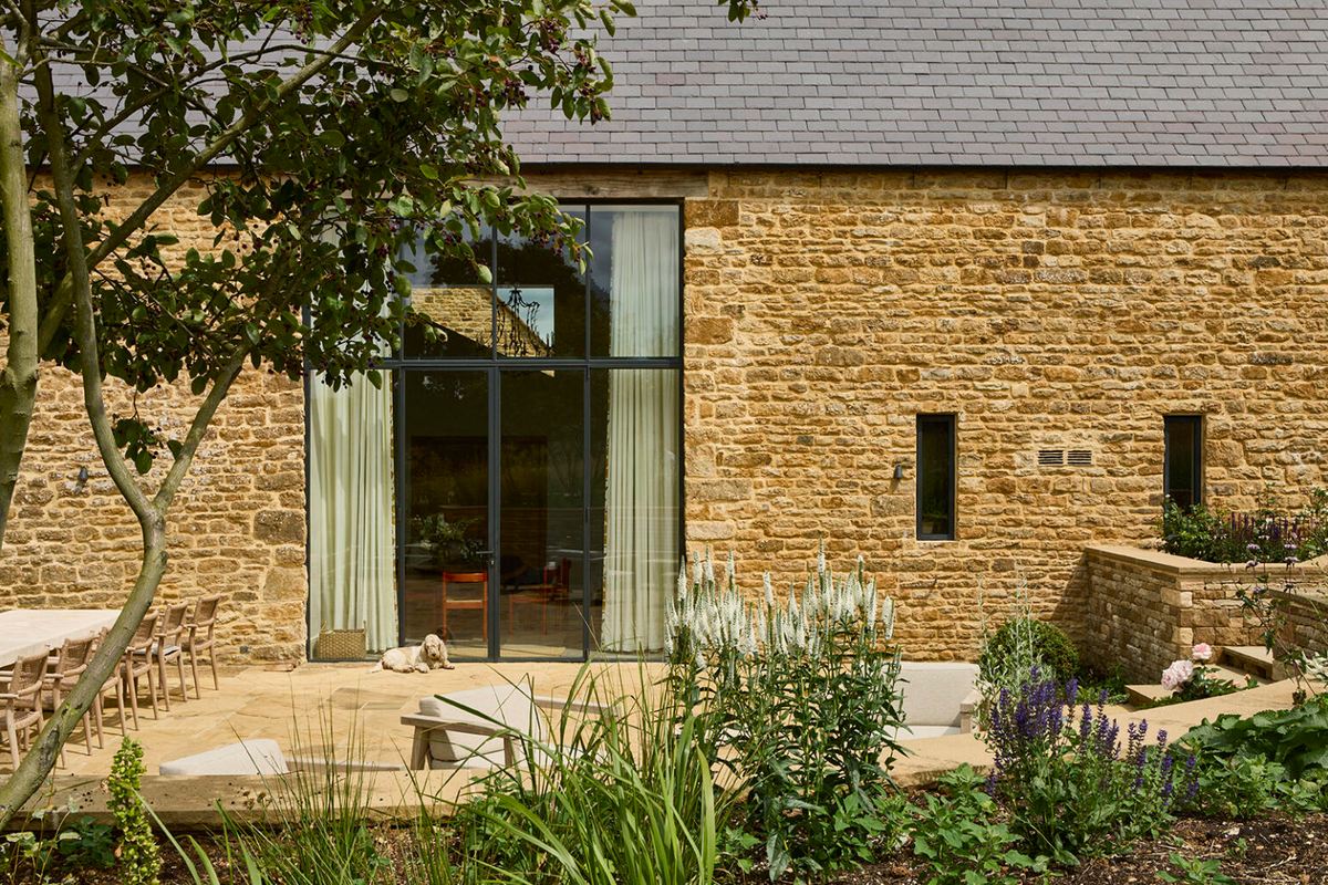 Leys Farm converted stone barn with full-height glazing opening onto a planted terrace